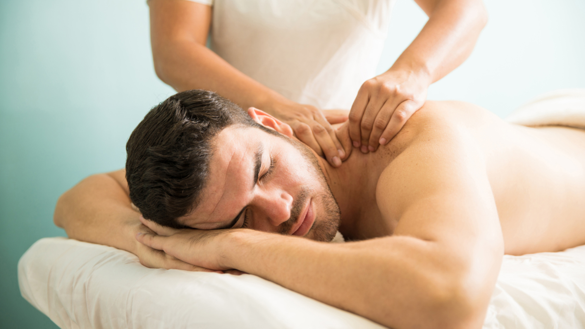 Very relaxed young Latin man getting a deep tissue massage on his back in a wellness and spa clinic